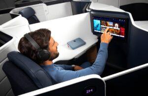 Air France: Business Class zum Wohlfühlen Mann sitzt in der Business Class von Air France und tippt mit dem Finger auf einen Bildschirm vor ihm, der auf der Rückseite des Vordersitzes integriert ist