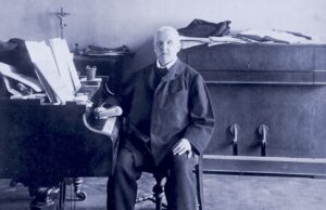 Anton Bruckner, der „fromme Revolutionär“ Der Komponist und Organist Anton Bruckner sitzt angelehnt an ein Klavier in seiner Wohnung