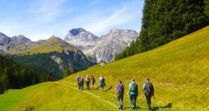 Gemeinsam wandern hilft gegen Einsamkeit Menschen wandern in einer grünen Alpenlandschaft in Richtung der Berge