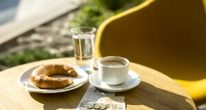 Wie halten Sie es mit Trinkgeld im Urlaub? Ein Tisch mit Kaffee, Kipferl und einigen Münzen und Geldschein als Trinkgeld