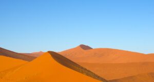 Die Wüste ruft, das Abenteuer der Stille lockt Mehrere Touristen erklimmen eine Düne in der Namib-Wüste