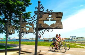 Mit dem Fahrrad die weite Welt erradeln Zwei Radfahrer auf einer Landstraße in Litauen passieren ein Symbol