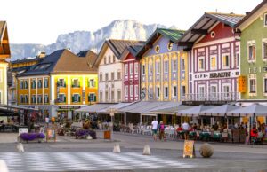 Meist gegoogelte Kleinstädte in Österreich Ortszentrum von Mondsee mit bunten Häusern am Abend. Dahinter Berge.