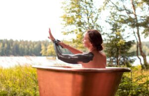 Wo Frauen der Schlamm des Bärensees hilft Eine Frau sitzt einer Kupferwann an einem See, ihre Hände sind mit Schlamm bedeckt