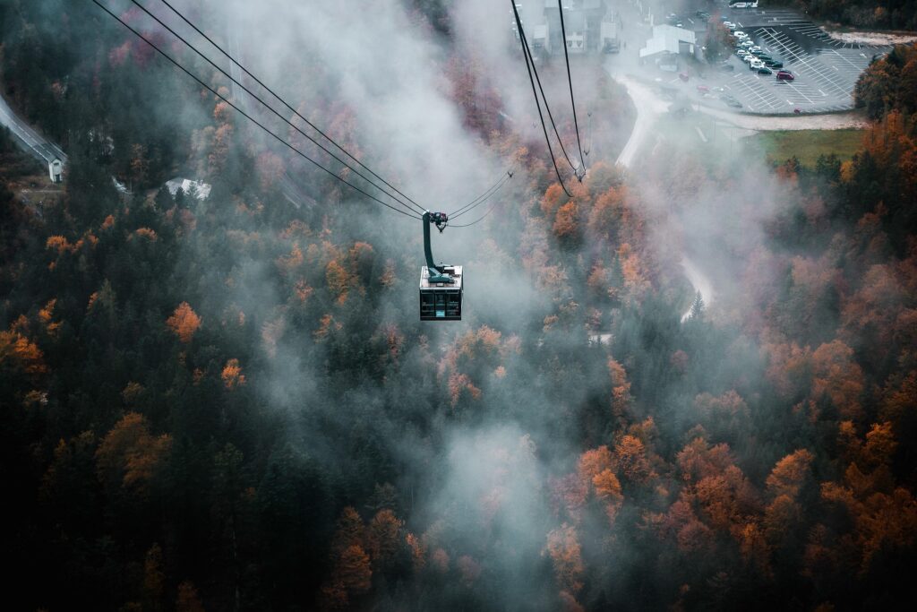 Eine Seilbahn im leichten Nebel über einer herbstlichen Landschaft