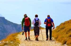 Bergurlaub ist europaweiter Sommertrend Drei Personen auf einem steinigen Weg durch eine Berglandschaft