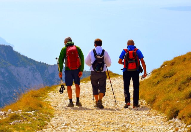 Drei Personen auf einem steinigen Weg durch eine Berglandschaft