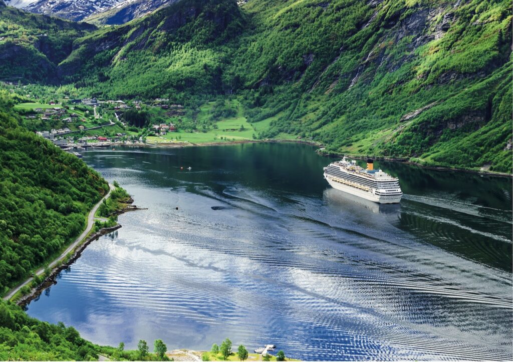 Costa-Kreuzfahrten: Der Geiranger Fjord gehört zu den Reisezielen. Dunkelblaues Wasser umgeben von grünerBerglandschaft, ein Schiff fährt Richtung Hafen