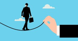 Reisesicherheitsplattform wird noch sicherer Resesicherheitsplattform wird noch sicherer: Illustration zeigt einen Mann mit Tasche auf einem Seil balancieren. Das Seilt hält eine Hand