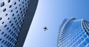 Blue Sky ist mehr als nur ein blauer Himmel Blue Sky: ein Flugzeug am Himmel zwischen zwei Wolkenkratzern