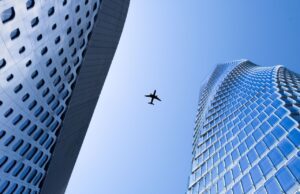 Blue Sky ist mehr als nur ein blauer Himmel Blue Sky: ein Flugzeug am Himmel zwischen zwei Wolkenkratzern