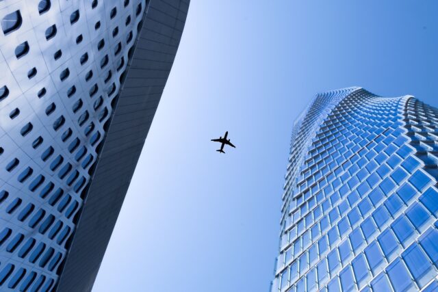 Blue Sky: ein Flugzeug am Himmel zwischen zwei Wolkenkratzern