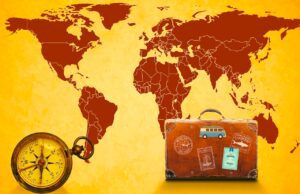 Reiselust der Österreicher bleibt 2025 hoch Weltkarte mit Kompass und einem Lederkoffer: Reiselust der Österreicher ist grenzenlos