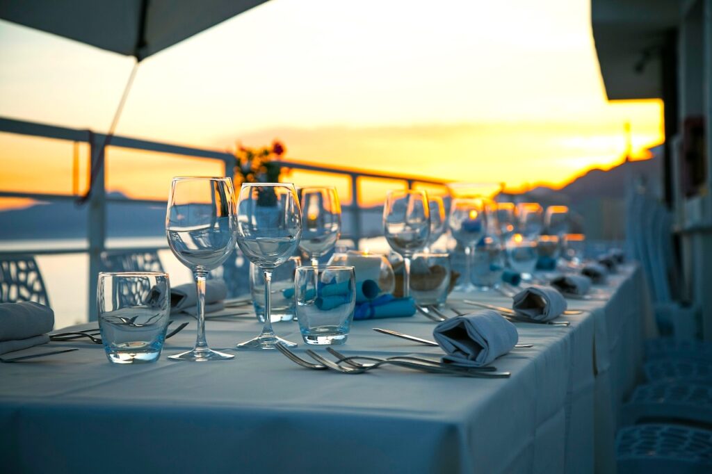 Die richtige Location gehört zu einer guten Veranstaltungsplanung: Ein langer gedeckte Tisch uf einer Terrasse bei Sonnenuntergang