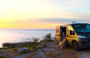 Vanlife – für mehr Reisefreiheit ohne Stress Vanlife ohne Stress: Eine Frau lehnt an einem Van und genießt den Ausblick
