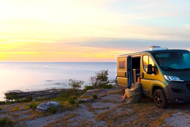 Vanlife ohne Stress: Eine Frau lehnt an einem Van und genießt den Ausblick