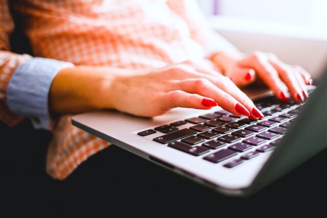 Eine Frauenhand mit lackierten Fingernägel gleitet über die schwarze Tastatur ihres Laptops: Sie nutzt das kostenlose WLAN an Bord von China Airlines