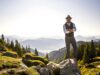 Bayern – direkt, kompetent und persönlich! Ein Mann mit Hut steht auf einem Berg in Bayern mit verschränkten Armen