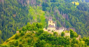 Urlaub in Österreich bleibt ein Reisemagnet Urlaub in Österreich: Mittelalterliche Berg in einer grünen Landschaft mit bewaldeten Bergen und Hütten