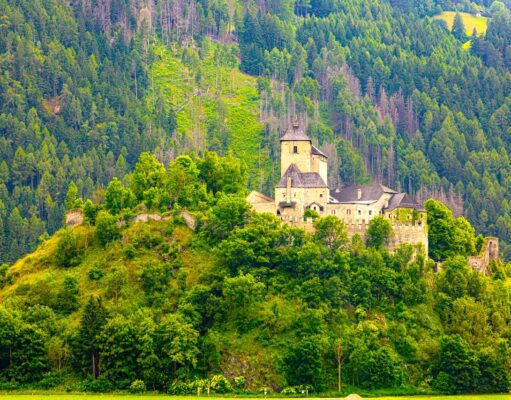 Österreich-Urlaub: Sichtbarkeit im Netz sinkt Österreich-Urlaub: Mittelalterliche Berg in einer grünen Landschaft mit bewaldeten Bergen und Hütten