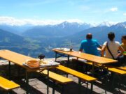 Gäste müssen sich angesprochen fühlen Mehrere Gäste sitzen auf einer Hüttenterrasse und blicken auf das Alpenpanorama