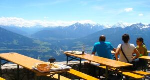 Gäste müssen sich angesprochen fühlen Mehrere Gäste sitzen auf einer Hüttenterrasse und blicken auf das Alpenpanorama