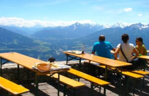Gäste müssen sich angesprochen fühlen Mehrere Gäste sitzen auf einer Hüttenterrasse und blicken auf das Alpenpanorama