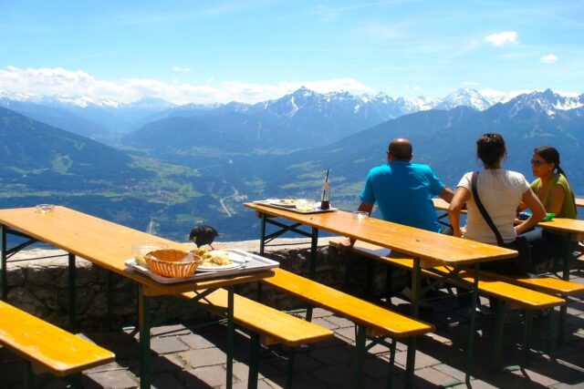 Wissen, was Gäste wirklich wollen Mehrere Gäste sitzen auf einer Hüttenterrasse und blicken auf das Alpenpanorama