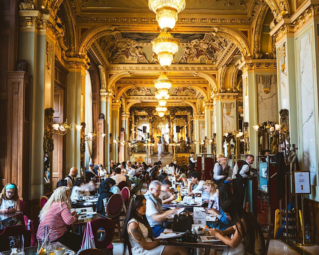 Im prachtvollen New York Café sitzen Touristen und Einheimische an vielen Tischen