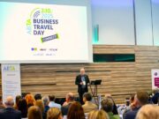 Business Travel Day Connect in Wien Connect Day: Ein Mann steht an einem Pult vor vielen Menschen und hält eine Rede. Im Hintergrund das Logo von ABTA eingeblendet