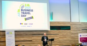 Business Travel Day Connect in Wien Connect Day: Ein Mann steht an einem Pult vor vielen Menschen und hält eine Rede. Im Hintergrund das Logo von ABTA eingeblendet