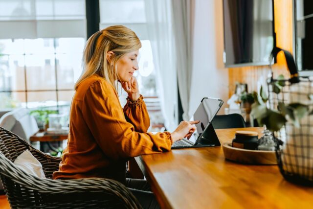 Frau sitzt im Home Office und blickt auf den Bildschirm ihres Laptops
