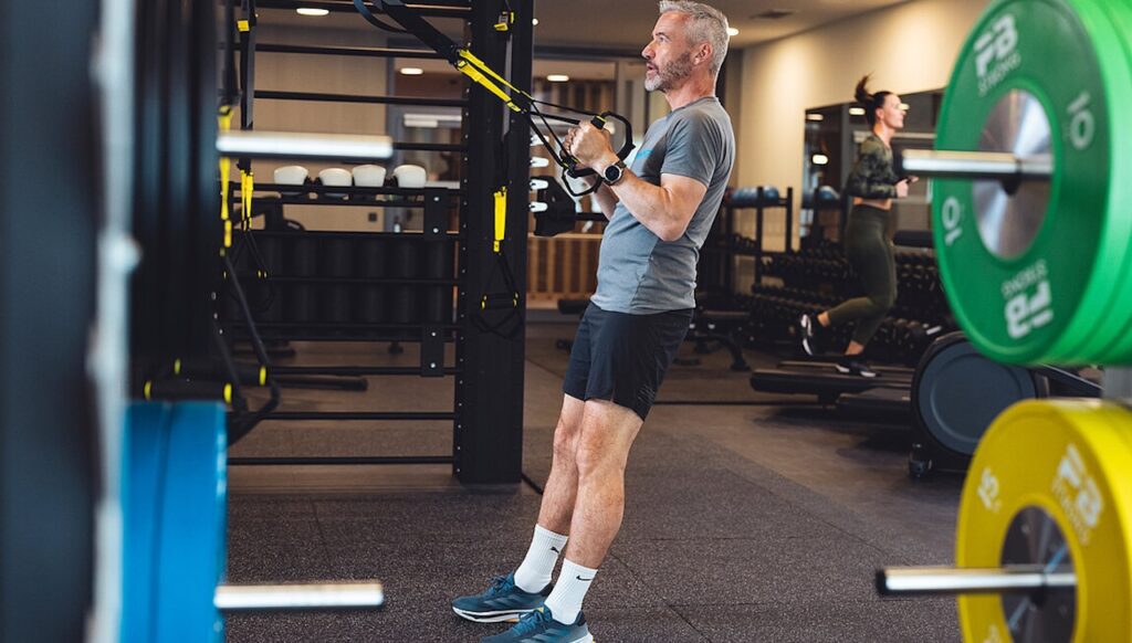 Ein Mann turnt in einem Fitnessraum: Hotels für Firmenevents müssen Räumlichkeiten für sportliche Aktivitäten anbieten