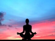 Garmisch-Partenkirchen im puren Yoga-Flow Sonnenuntergang und eine Frau hock in einer Yoga-Pose und blickt auf dem blauen Himmel mit dem rötlichen Licht der untergehenden Sonne