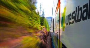 Bahnfahren einfach wie Musik-Streaming? Bahnfahren: Dynamische Aufnahme eines Zuges mit der Beschriftung Westbahn vorbei an herbstlichen Sträuchern