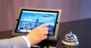 Wie werden Hotelprogramme gehandhabt? Studie über Hotelprogramme: Die Hand eines Mannes berührt den Bildschirm eines Tablets
