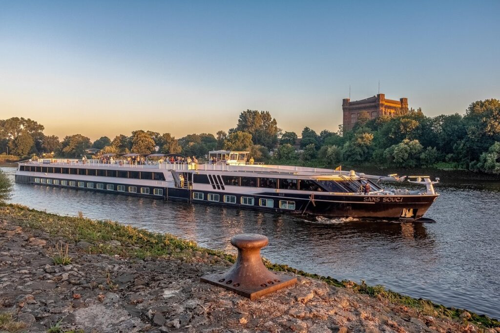 Flusskreuzfahrten boomen: Eine Kreuzfahrtschiff unterwegs auf einem Fluss in Frankreich, im Hintergrund eine Festung zu sehen.