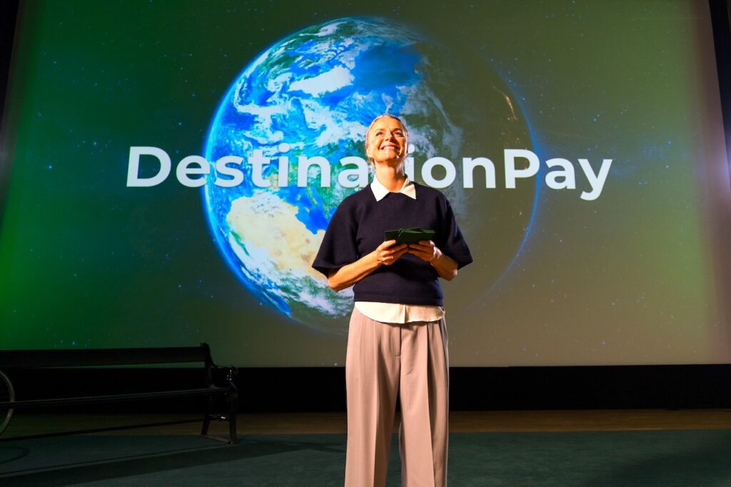 Rikke Holm Petersen, Marketingchefin, bei der Präsentation von DestinationPay in Kopenhagen vor einem Globus mit der ein geblendeten Schrift <destinationPay