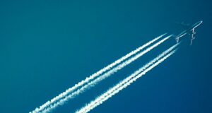 Dekarbonisierung der Luftfahrt unbezahlbar Dekarbonisierung: Passagiere am blauen Himmel mit Kondensstreifen