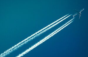 Dekarbonisierung der Luftfahrt unbezahlbar Dekarbonisierung: Passagiere am blauen Himmel mit Kondensstreifen