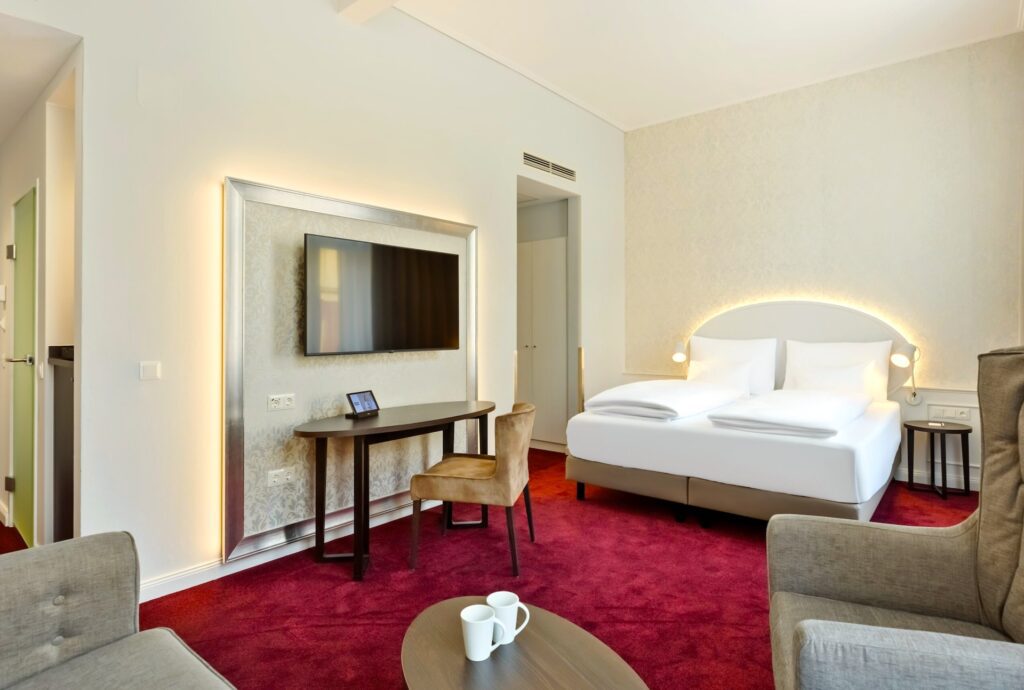 Premiumzimmer im Rathaushotel Wien mit rotem Teppichboden, TV-Geräte an der Wand