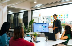 Wie KI im Travel Management Kosten senkt KI im Travel Management spart Kosten und viel Zeit: Ein Büro mit Mitarbeitern und einem gro0en Monitor