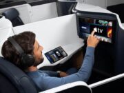 Apple TV auf Air France-Langstreckenflügen Flugreisender greift auf einem Bildschirm in einer Air France Maschine nach demApple TV Programm