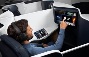 Apple TV auf Air France-Langstreckenflügen Flugreisender greift auf einem Bildschirm in einer Air France Maschine nach demApple TV Programm