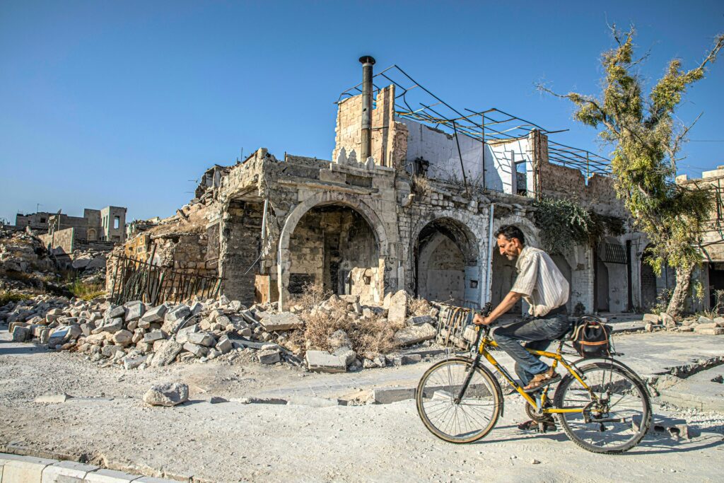 Sicherheitslage: Reisewarnungen für Nahosten Mann Radelt Durch Kriegszerstörte Ruinen Von Aleppo