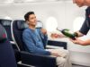Air France erhöht das Reiseerlebnis in der Premium-Kabine Air France steigert das Reiseerlebnis in der Premium-Kabine: Ein sitzt im Flugzeug und eine Flugbegleiterin scheint ihm aus einer Flache Champagner ein