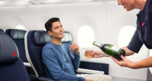Air France erhöht das Reiseerlebnis in der Premium-Kabine Air France steigert das Reiseerlebnis in der Premium-Kabine: Ein sitzt im Flugzeug und eine Flugbegleiterin scheint ihm aus einer Flache Champagner ein