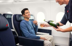 Air France erhöht das Reiseerlebnis in der Premium-Kabine Air France steigert das Reiseerlebnis in der Premium-Kabine: Ein sitzt im Flugzeug und eine Flugbegleiterin scheint ihm aus einer Flache Champagner ein