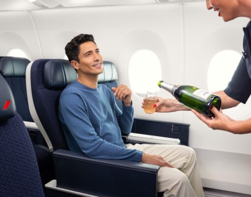 Air France erhöht das Reiseerlebnis in der Premium-Kabine Air France steigert das Reiseerlebnis in der Premium-Kabine: Ein sitzt im Flugzeug und eine Flugbegleiterin scheint ihm aus einer Flache Champagner ein