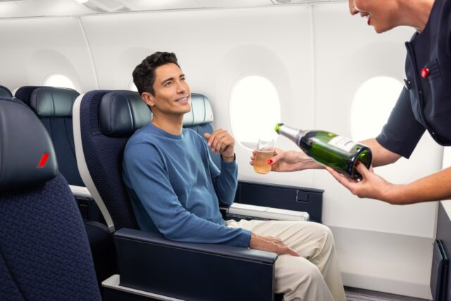 Air France und das Reiseerlebnis in der Premium-Kabine Air France steigert das Reiseerlebnis in der Premium-Kabine: Ein sitzt im Flugzeug und eine Flugbegleiterin scheint ihm aus einer Flache Champagner ein